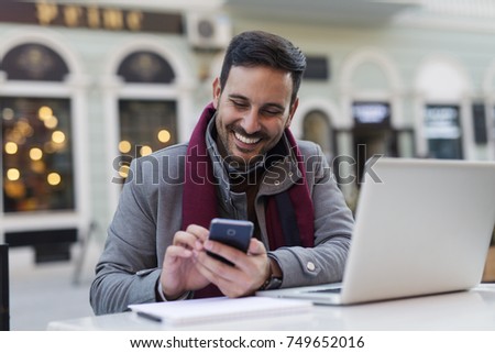 Attractive young man using his phone at the coffee shop