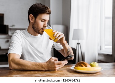 attractive young man using smartphone during breakfast at home - Powered by Shutterstock