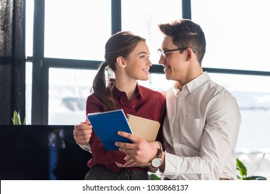 Attractive Young Managers Couple Embracing At Office, Workplace Romance Concept