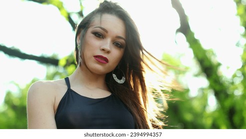 Attractive young millennial woman posing looking to camera with lens-flare sunlight in outdoor park - Shutterstock ID 2394994357