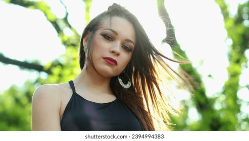 Attractive young millennial woman posing looking to camera with lens-flare sunlight in outdoor park - Shutterstock ID 2394994383