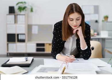 Attractive Young Office Woman Working On The Business Papers While Leaning On Her Desk.