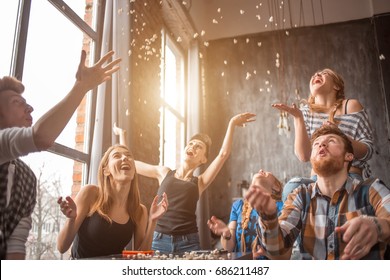 Attractive young people throwing popcorn and enjoying together.