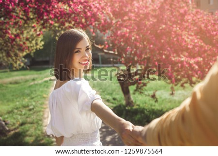 Attractive young people walking in park. Pretty couple together. Woman and man inlove. Girl taking her boyfriend by the hand outdoor