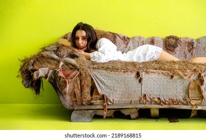 Attractive, Young, Sexy, Sensual, Seductive Woman On Old Tattered Scrap Junk Couch Recliner Recamiere, In White Nightwear