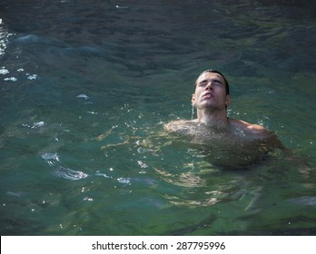 Attractive Young Shirtless Athletic Man Emerging From Water By Sea Or Ocean Shore, Eyes Closed