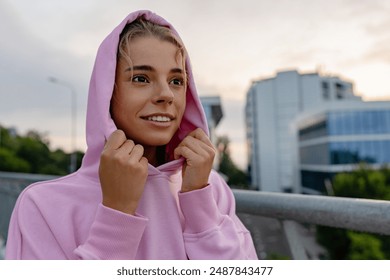 attractive young smiling woman in stylish sportswear in pink hoodie doing sports in morning outdoors, stretching, healthy lifestyle, skinny strong body - Powered by Shutterstock