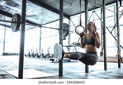 Attractive Young Sporty Woman Is Working Out In Gym. Cross Fit Training. Muscular Woman With Athletics Rings