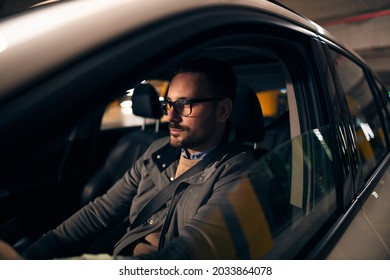 Attractive Young Successful Man With Glasses Driving Car At Night