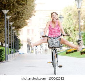 Attractive young tourist woman visiting a destination city and riding a bike in a wide avenue, stretching her legs and having a fun and excitement expression, outdoors. - Shutterstock ID 153062312