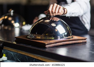 Attractive Young Waiter In Tuxedo Holding Serving Tray With Metal Cloche And Napkin