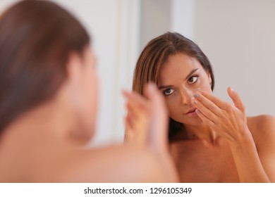 Attractive young woman applying cream on her Face