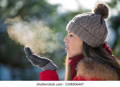 Attractive young woman breathe out steam outdoor in winter