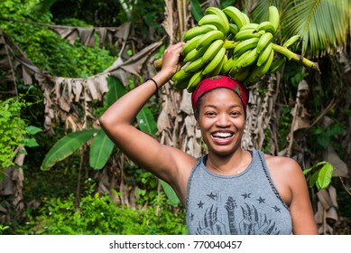 Attractive young woman with a bunch of green bananas on her head