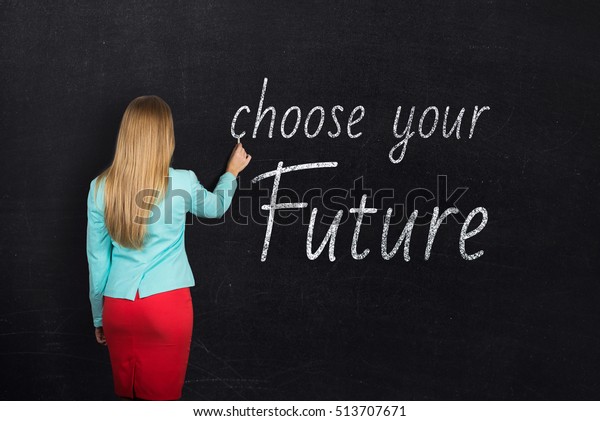 An attractive young teacher with chalk at the blackboard with text choose your future. Learning motivation.