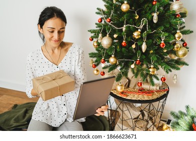 Attractive young woman chatting online, congratulating family or friends with digital tablet.
Video chat with parents and grandparents on Christmas Eve. Christmas video greeting. 
