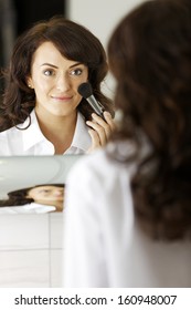 Attractive Young Woman Doing Her Makeup In Front Of The Bathroom Mirror.