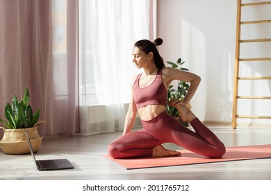 Attractive Young Woman Doing Stretching Online At Home Under Guidance Of Professional Trainer Online. Self-isolation And Social Distance During Covid Pandemic. Health Care, Life Balance Concept 