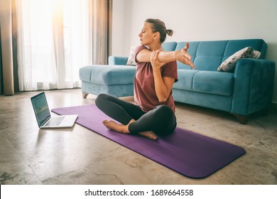 Attractive young woman doing yoga stretching yoga online at home. Self-isolation is beneficial, entertainment and education on the Internet. Healthy lifestyle concept. - Shutterstock ID 1689664558