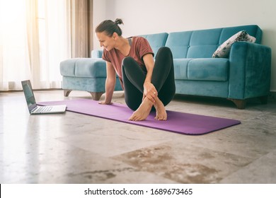 Attractive young woman doing yoga stretching yoga online at home. Self-isolation is beneficial, entertainment and education on the Internet. Healthy lifestyle concept. - Shutterstock ID 1689673465