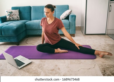 Attractive young woman doing yoga stretching yoga online at home. Self-isolation is beneficial, entertainment and education on the Internet. Healthy lifestyle concept. - Powered by Shutterstock