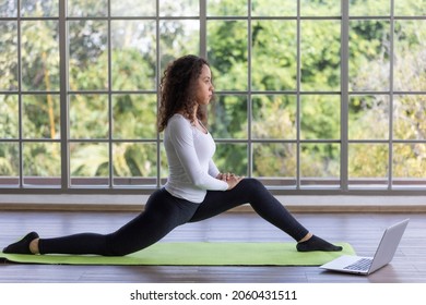 Attractive young woman doing yoga stretching yoga online at home, exercise at home