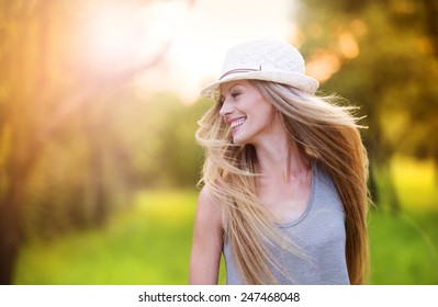 Attractive young woman enjoying her time outside in park with sunset in background.