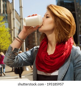Attractive Young Woman Enjoying A Hot Drink In A White Paper Cup Against Cityscape Background