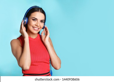 Attractive Young Woman Enjoying Music In Headphones On Color Background. Space For Text