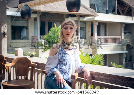 Attractive young woman in ethnic style look posing in tropical restaurant, portrait. 