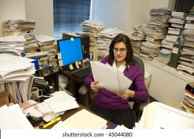 Attractive young woman executive at work in a very messy office
