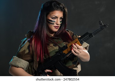 Attractive Young Woman With Face Paint On War Paint In Uniform Holding An Automatic Rifle.