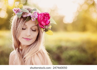 Attractive young woman with flower wreath on her head with sunset in background. - Powered by Shutterstock