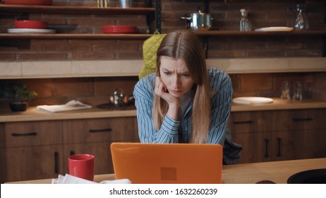 Attractive Young Woman Freelancer Drinking Coffee Starting Her Work In The Kitchen At Home. Portrait Of Embarassed Girl Having Trouble With A Laptop Looking At Dark Screen.