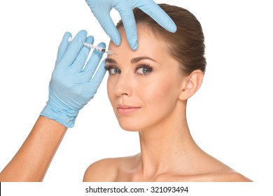 Attractive young woman gets cosmetic injection, isolated over white background. Doctors hands making an injection in face. Beauty Treatment.