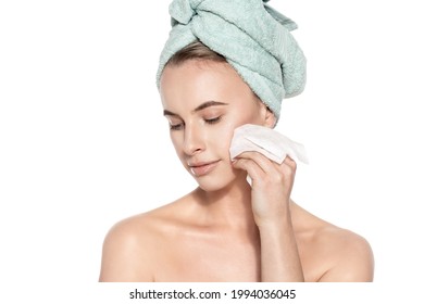 Attractive Young Woman With Her Hair Wrapped In A Towel, Removing Make Up. Pretty Girl With Perfect Complexion Cleansing Her Face Using Soft Face Wipe. Isolated On White Background. 