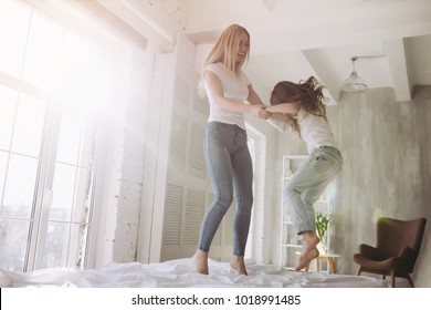 Attractive young woman and her little cute daughter are having fun in bed while being at home together. Happy Mother's Day! - Shutterstock ID 1018991485