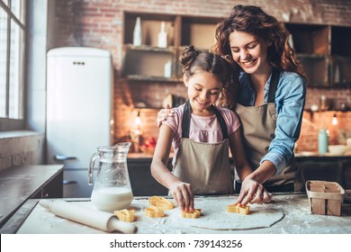 Attractive Young Woman And Her Little Cute Daughter Are Cooking On Kitchen. Having Fun Together While Making Cakes And Cookies.