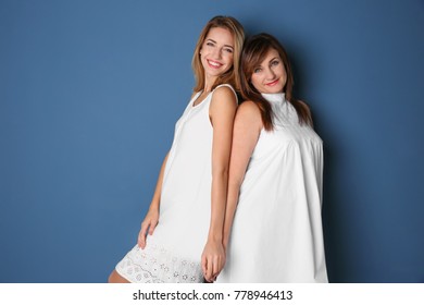 Attractive Young Woman With Her Mother In Matching Dresses On Color Background