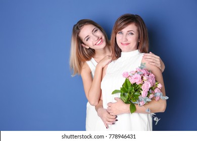 Attractive Young Woman With Her Mother In Matching Dresses On Color Background