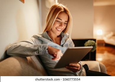 Attractive young woman holding a tablet at home - Powered by Shutterstock