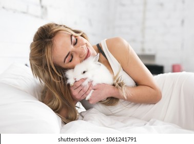 Attractive young woman hugging white rabbit.