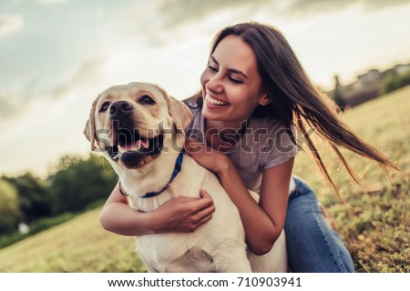 Attractive young woman with labrador outdoors. Woman on a green grass with dog labrador retriever.