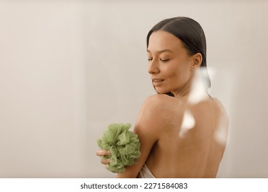 Attractive young woman with long hair does anti-cellulite massage with soft massage washcloth for the body and legs. Close-up of slender figure. Cosmetology and healthy body care.