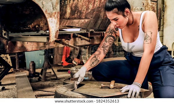 Attractive young woman mechanical worker\
repairing a vintage car in old\
garage.