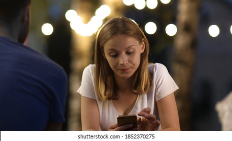 Attractive Young Woman On A Date Using Mobile Phone And Does Not Pay Attention To The Boy.