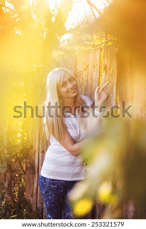 Attractive young woman outside next to the wooden fence.