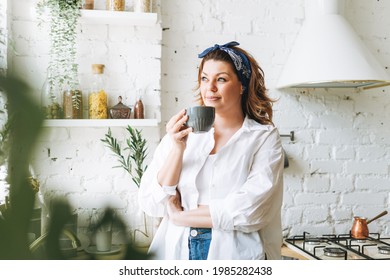 Attractive Young Woman Plus Size Body Positive In Blue Jeans And White Shirt Drink Morning Coffee At Home Kitchen