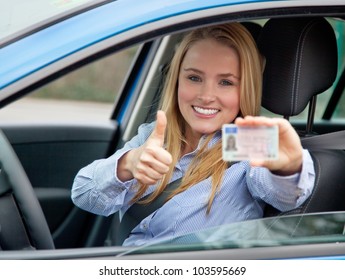 Attractive young woman proudly showing her drivers license.