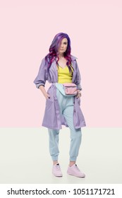 Attractive Young Woman In Purple Trench Coat With Waist Pack On Creative Background